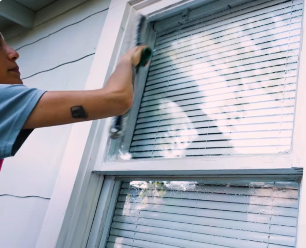 Close-up of a brush tool cleaning a window frame edge on a San Clemente home