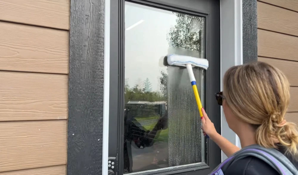 Window cleaning technician applying cleaning solution to an exterior window with an applicator