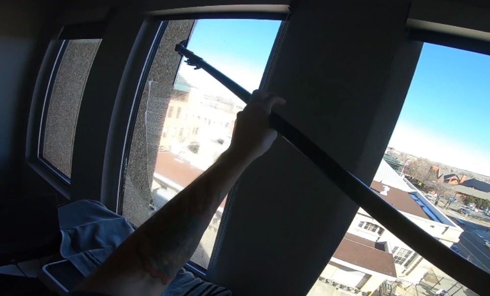Technician using an extension pole to reach upper interior windows in a San Clemente office building
