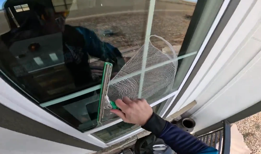 Close-up of a window cleaning technician using a squeegee on a residential exterior window