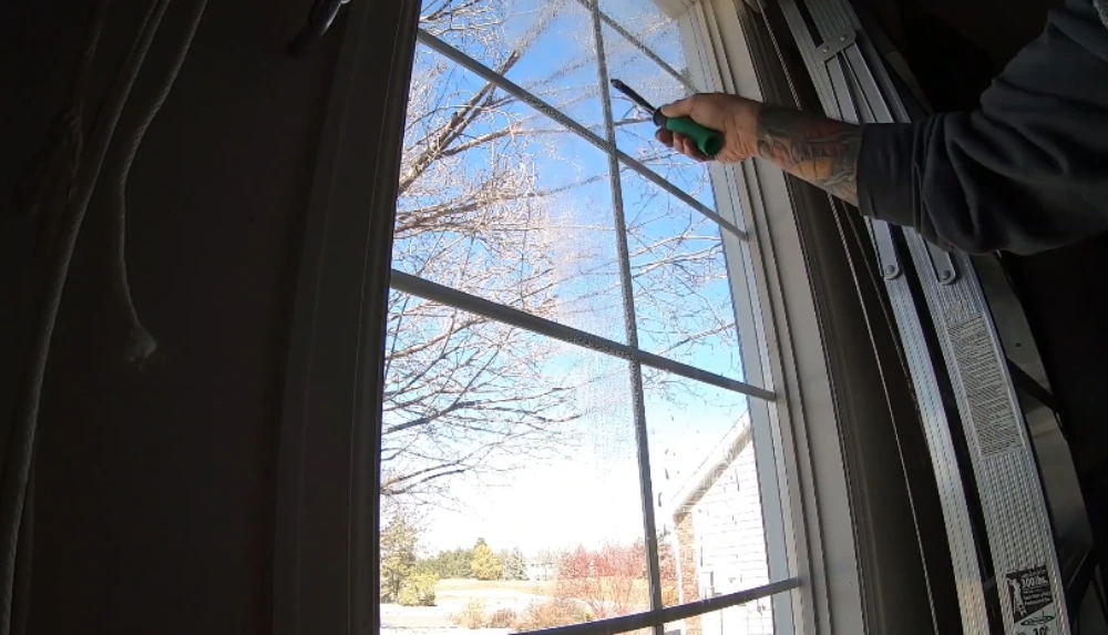 Close-up of squeegee tool cleaning interior grid-pane window glass in San Clemente