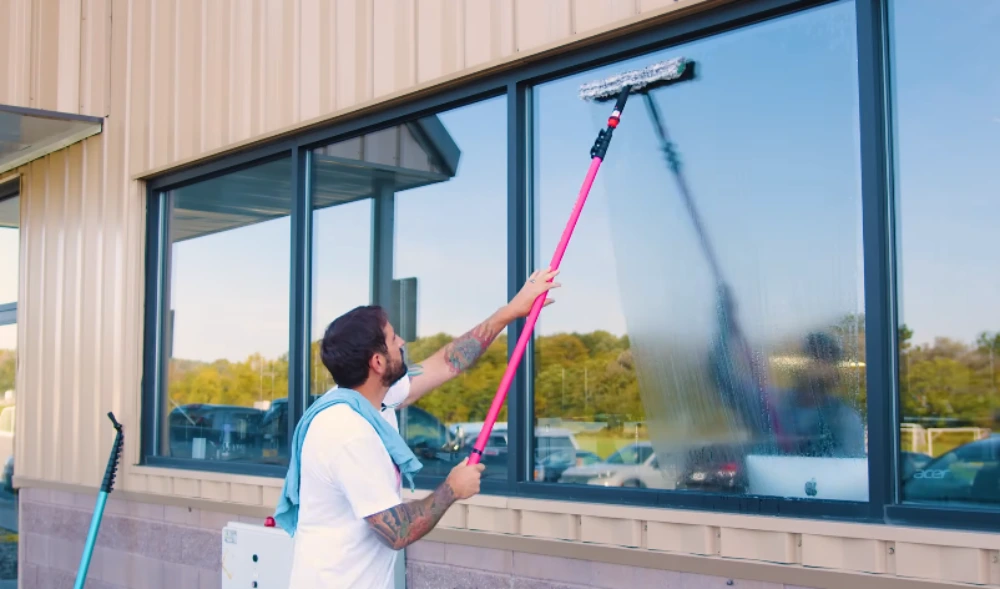 Commercial window cleaner using a water-fed extension pole on upper-story business windows in San Clemente
