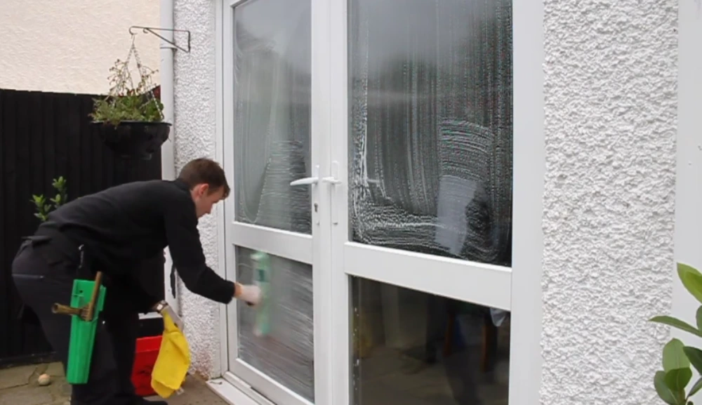 Window cleaning technician cleaning glass French doors on a residential exterior